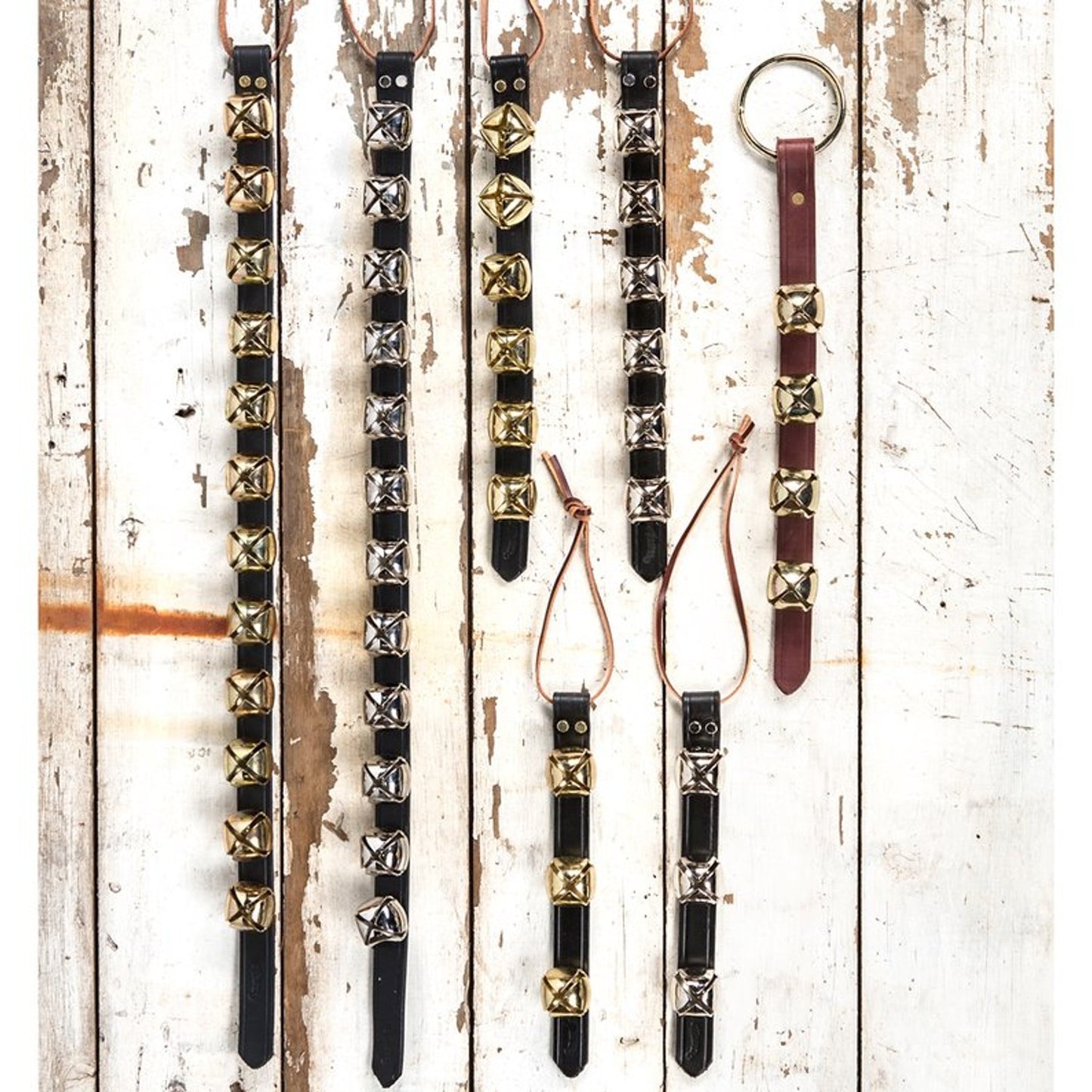 Selection of handcrafted sleigh bell door hangers with alternating brass and silver bells on black leather straps and one with brown leather, ideal for holiday decor, USA Made, Home & Decor, Best Sellers, and Promo Eligible collections.
