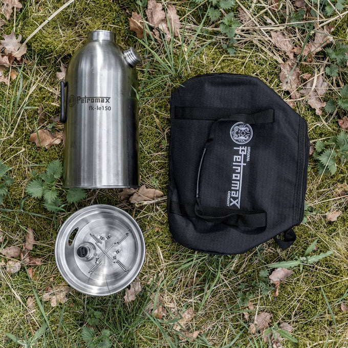 Disassembled stainless steel fire kettle with screw-on spout, stove base, and black carrying case, laid on grass; suitable for Farm, Garden & Tool, Camping, Emergency Supplies, Best Sellers, and Promo Eligible collections.