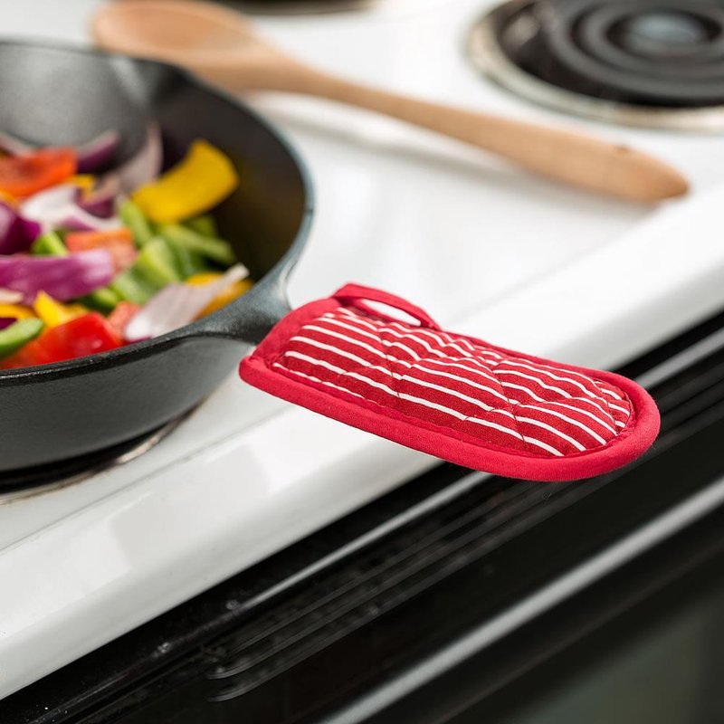 Red striped hot handle pad snugly fitted over a cast iron skillet handle on a white stove with colorful sautéed vegetables, featured in Kitchen & Food, Cookware, Cast Iron, and Best Sellers collections.