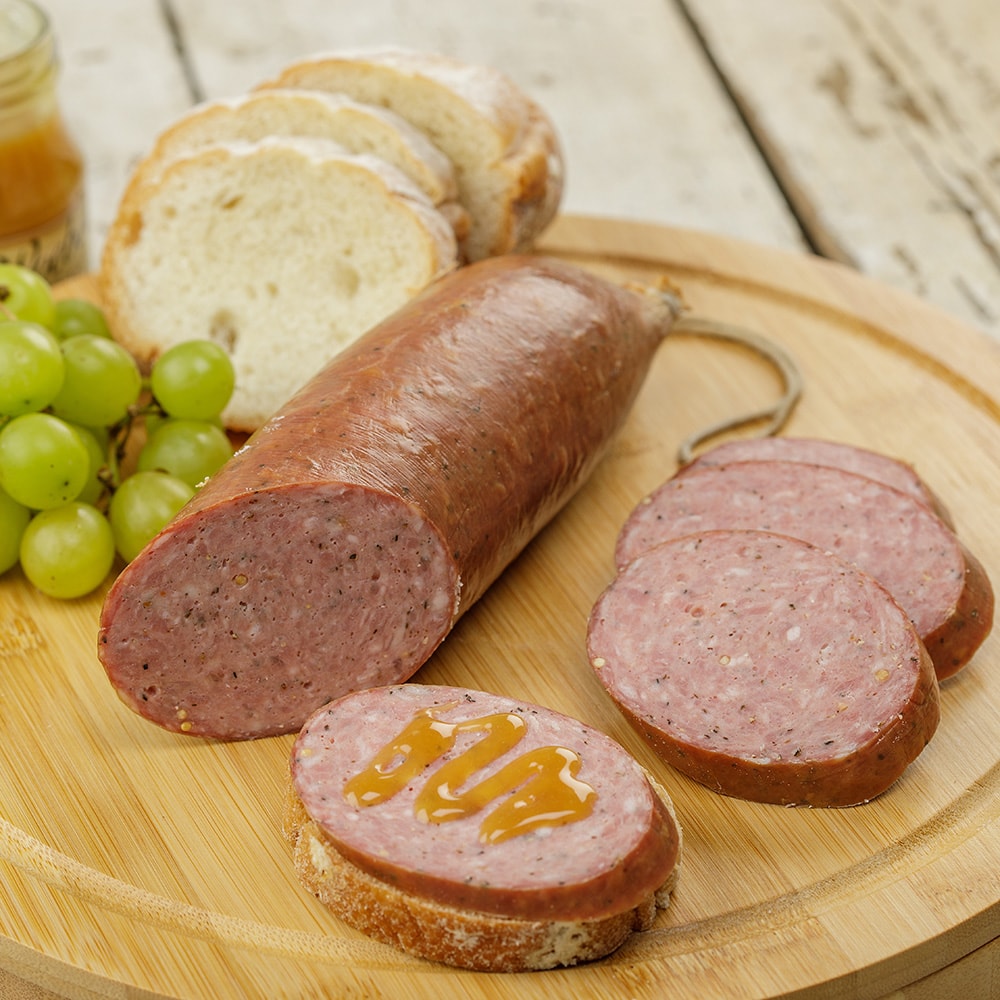 Handcrafted summer sausage from Amish Country, sliced and arranged on a wooden board with green grapes, bread slices, and honey drizzle, ideal for Kitchen & Food, Snacks and Sweets, Pantry, Meats, USA Made, and Best Sellers collections.