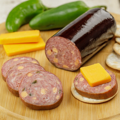 Handcrafted Amish Country summer sausage made in USA with pork and beef blend, featuring chunks of cheese, sliced on a wooden board with cheddar, crackers, and green peppers, perfect for Kitchen & Food, Snacks and Sweets, Pantry, Meats, USA Made, and Best Sellers collections.