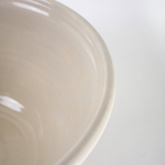 Close-up of a handcrafted cream stoneware mixing bowl with subtle blue stripes, made in USA, ideal for Kitchen & Food, Cookware, Baking Supplies, and Storage collections.