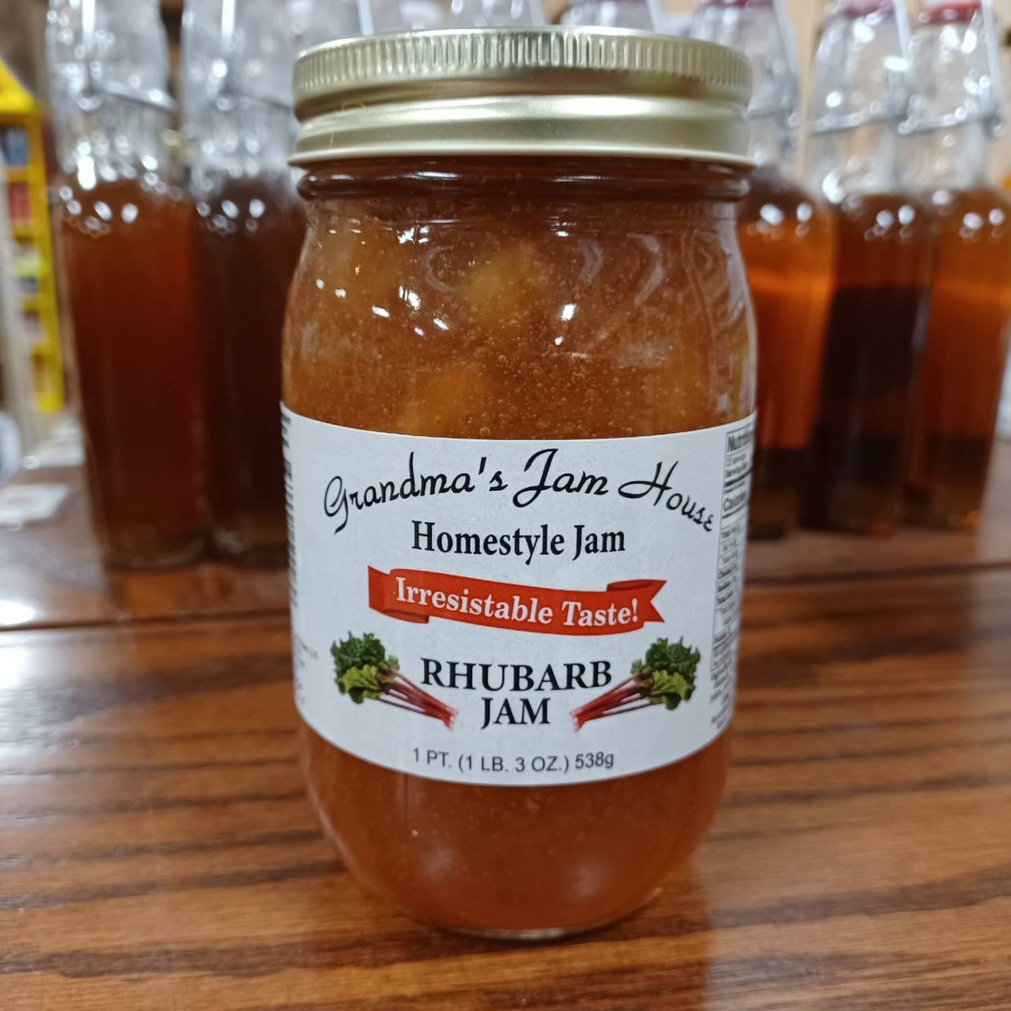 Glass jar of handcrafted rhubarb jam with gold lid and white label featuring rhubarb illustrations and "Irresistable Taste" banner, made in USA, ideal for Kitchen & Food, Pantry, Peanut Butter & Jellies, Best Sellers, and Promo Eligible collections.