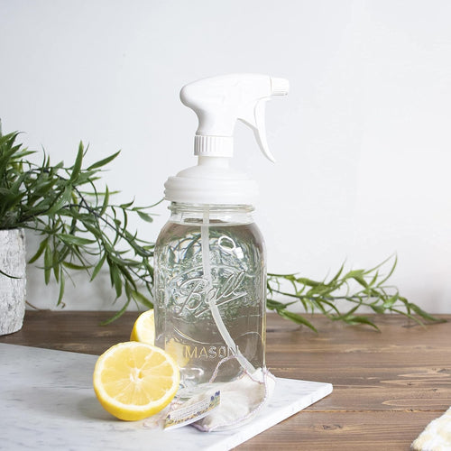 Clear regular-mouth mason jar with a white sprayer lid dispensing liquid, set on wooden surface near fresh lemon halves and green plant, part of Home & Decor, Household Helpers, USA Made, Best Sellers collections.