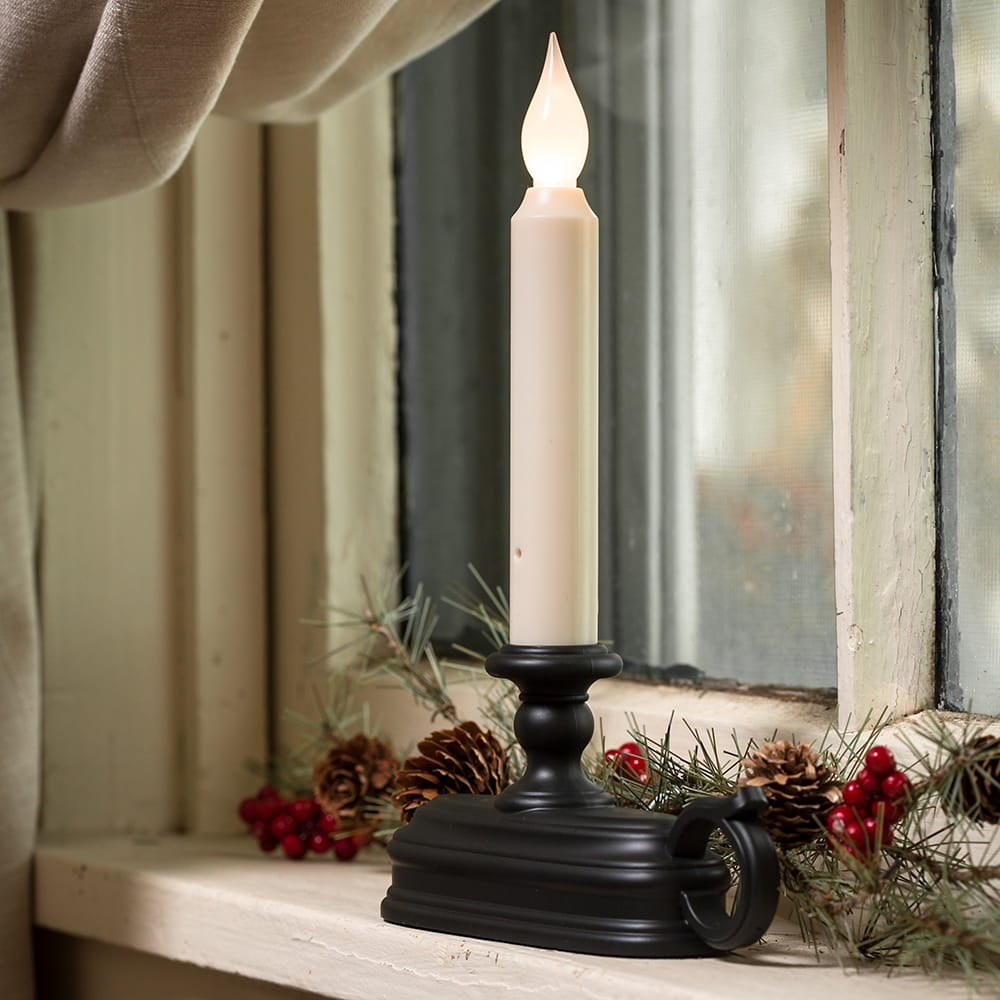 LED candle in a black holder emitting warm white light on a rustic window sill decorated with pinecones and red berries, perfect for Holiday Decor and Home & Decor collections.