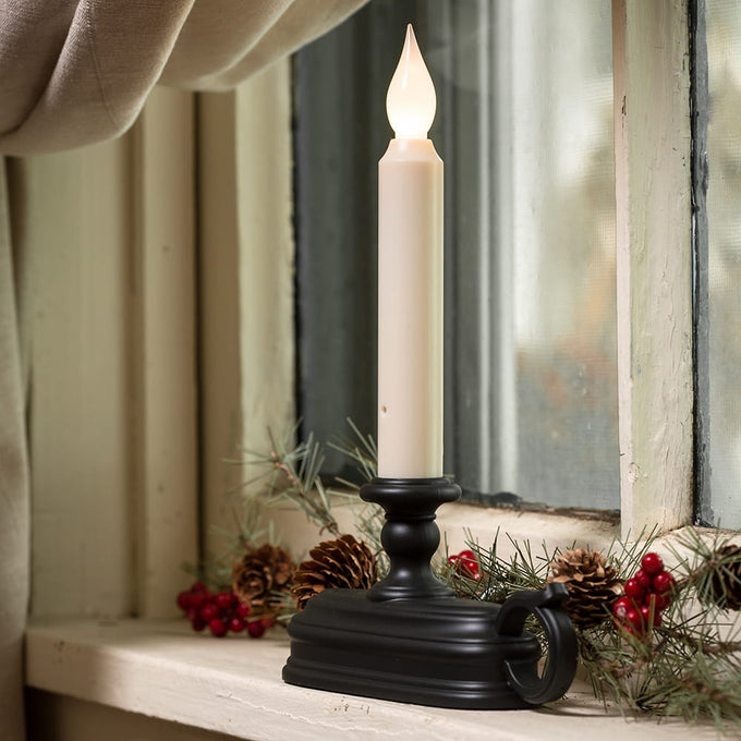 LED candle in a black holder emitting warm white light on a rustic window sill decorated with pinecones and red berries, perfect for Holiday Decor and Home & Decor collections.