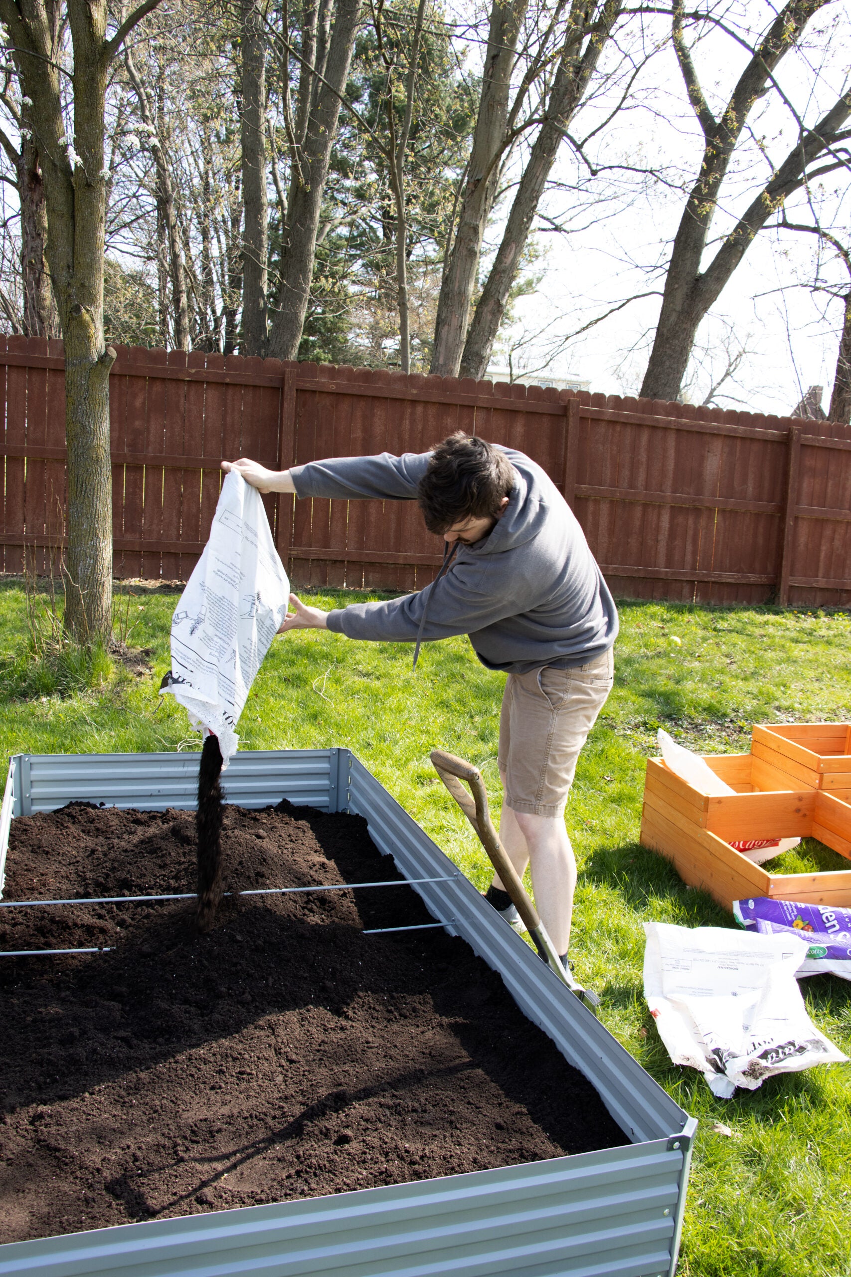 pouring soil into a raised garden bed.