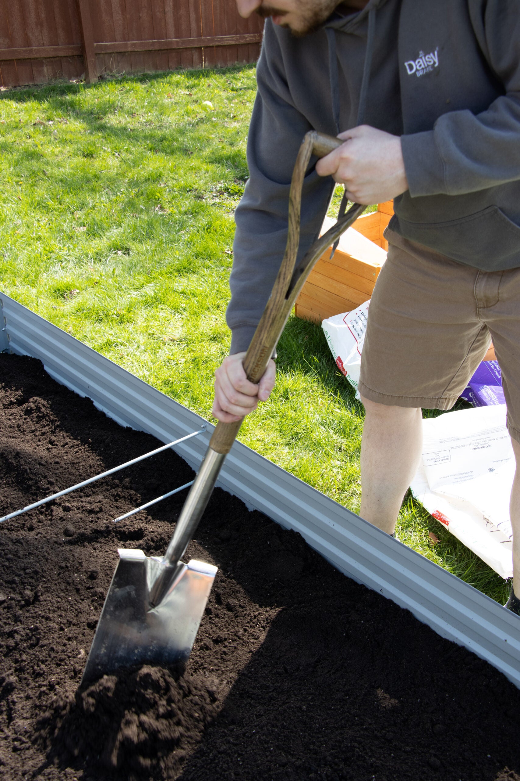 A Spear & Jackson shovel smooths out soil in a garden bed.