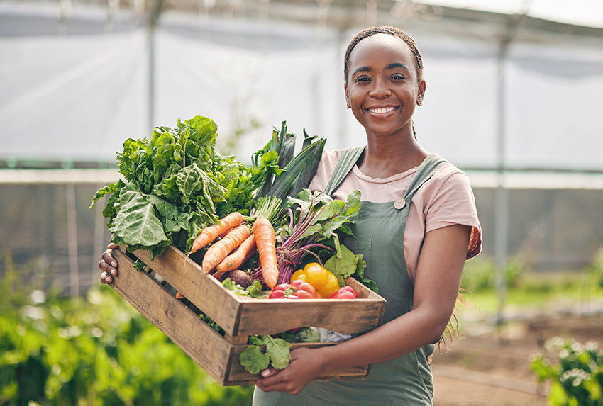 Young woman with crate of produce from greenhouse garden