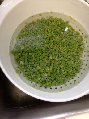 After blanching, plunge peas into ice water to stop cooking. I pour them into a colander, and plunge into a sanitized sink full of ice and water. Peas cool in less than a minute. Note the brighter green color after blanching.