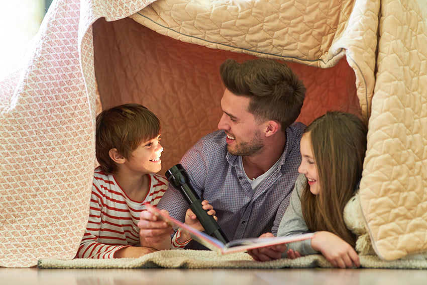 family reading in blanket tent